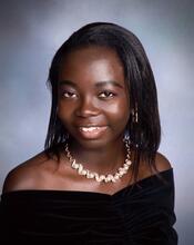 A picture of Aderonke Adejare, a Black woman with Black hair wearing a Black dress and a necklace